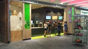 The CRAVE store entrance lit with green LED strip lighting, digital menu screens mounted above the serving counter