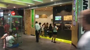 Customers at the CRAVE counter, with illuminated green floor edging and backlit signage either side of the entrance