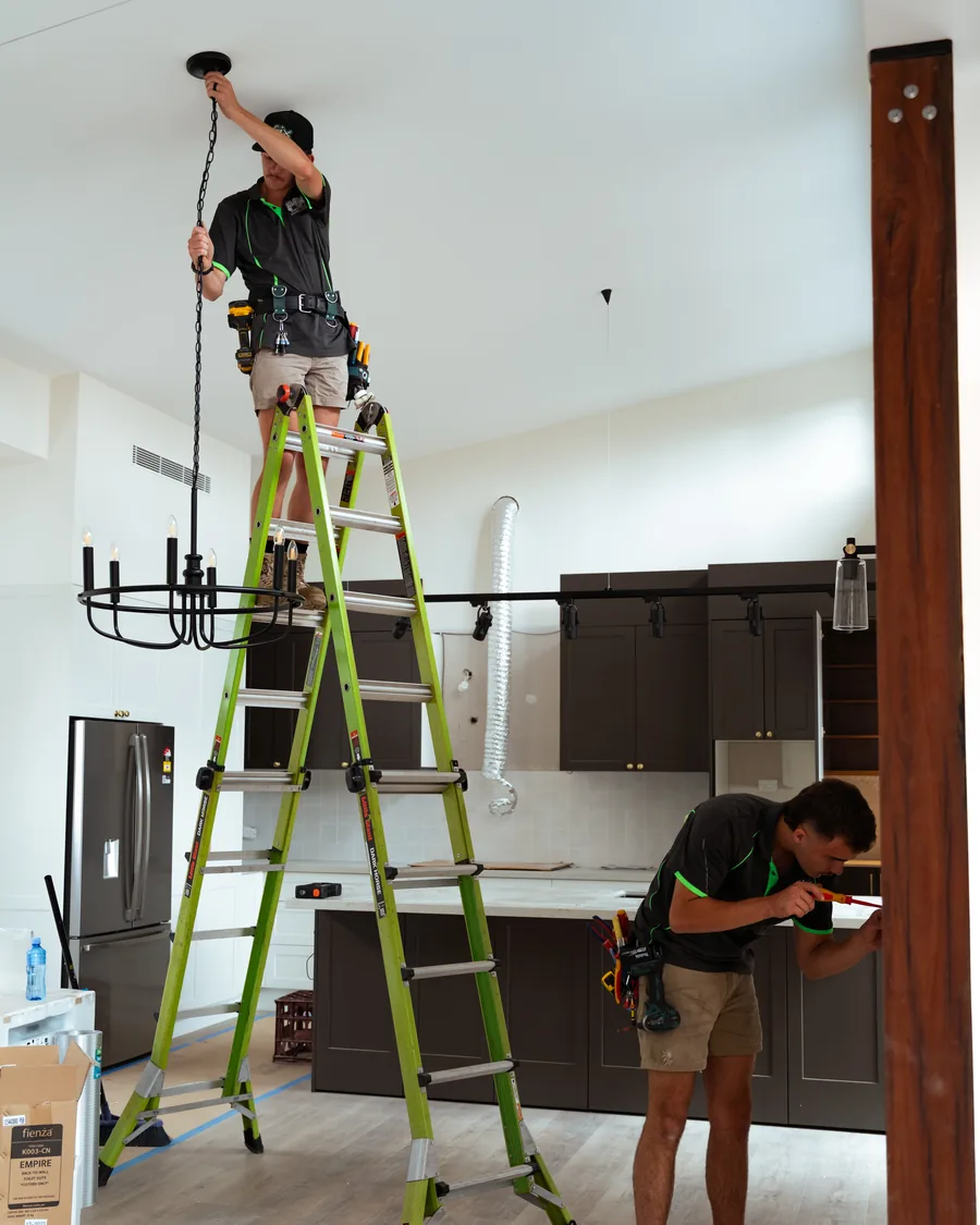 Two electricians running lighting in a new build