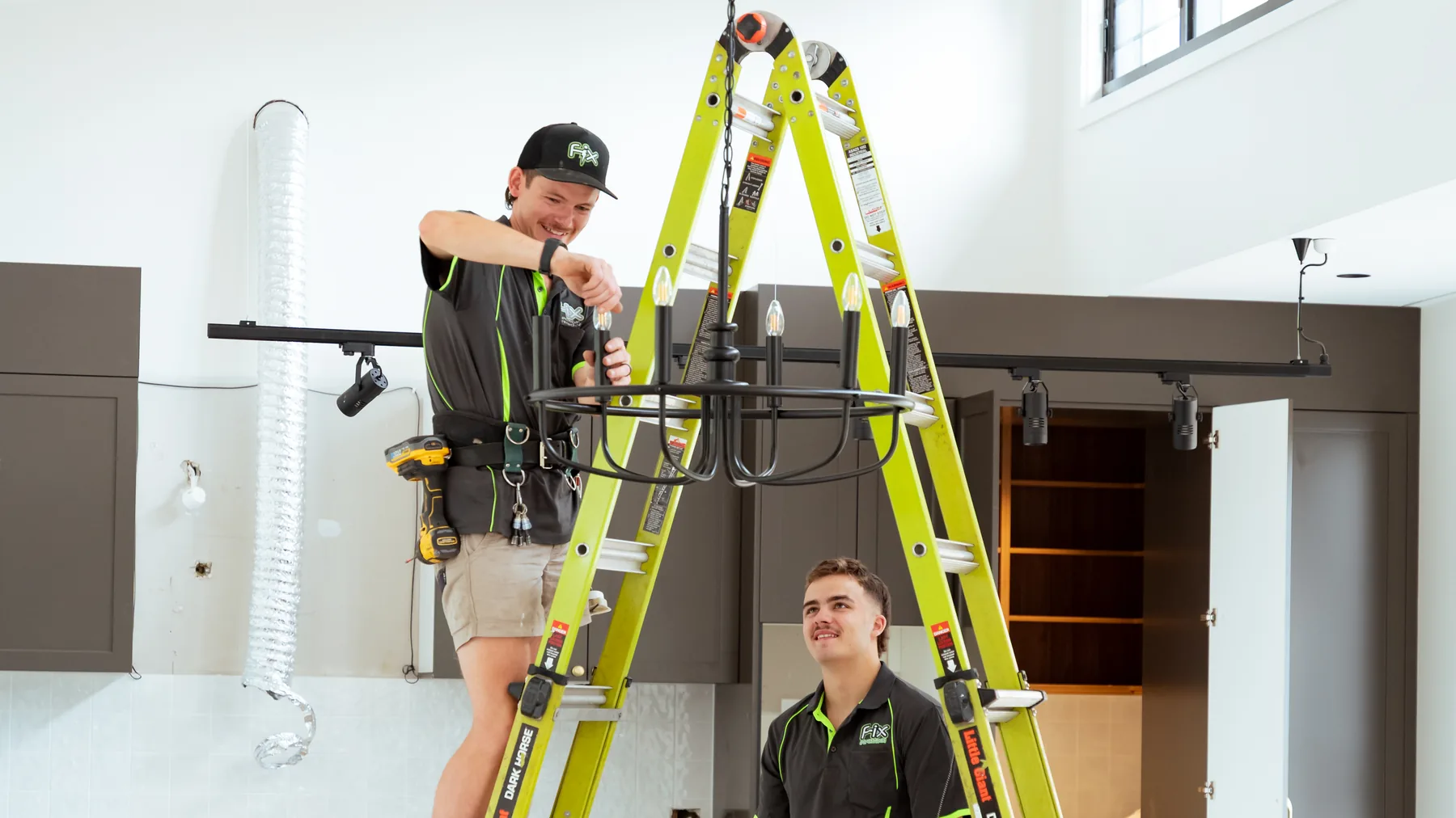 Electricians installing a pendant in a new kitchen