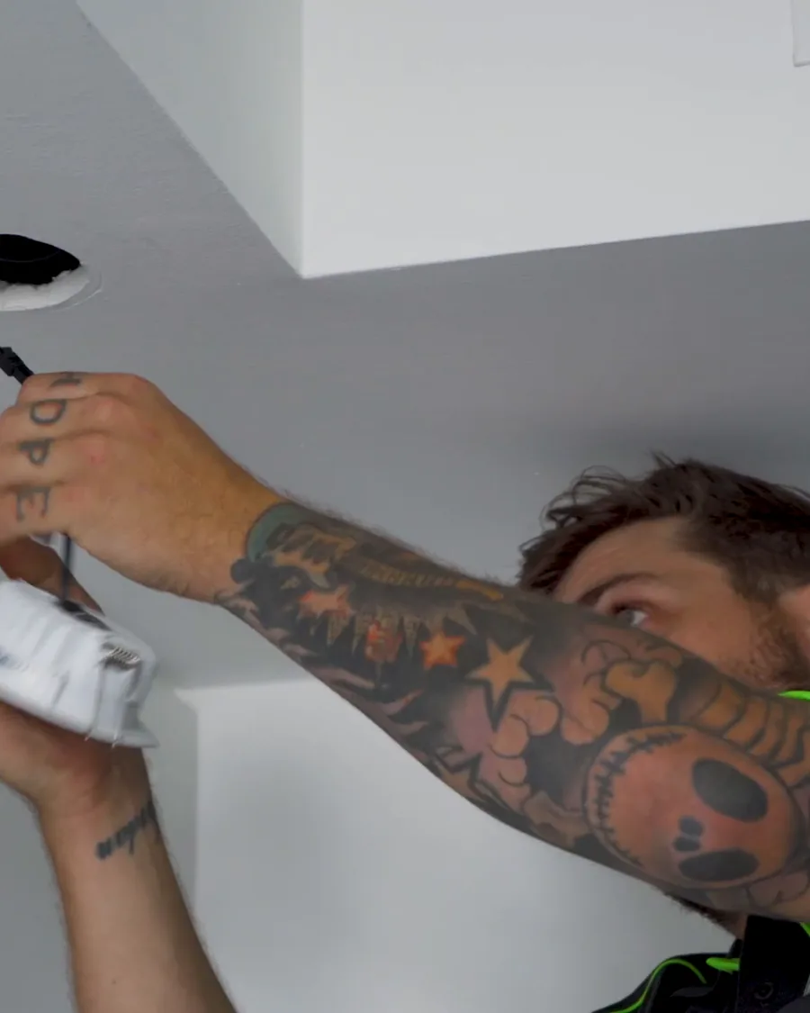 Electrician fitting a downlight in a commercial ceiling