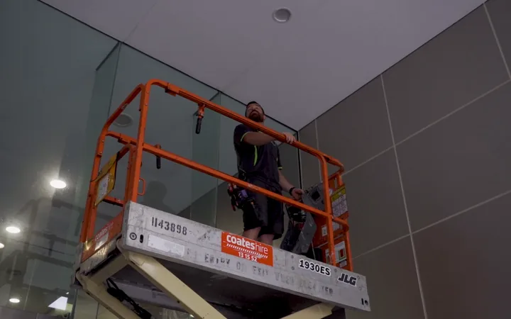 Electrician working at height from a lift in an industrial interior