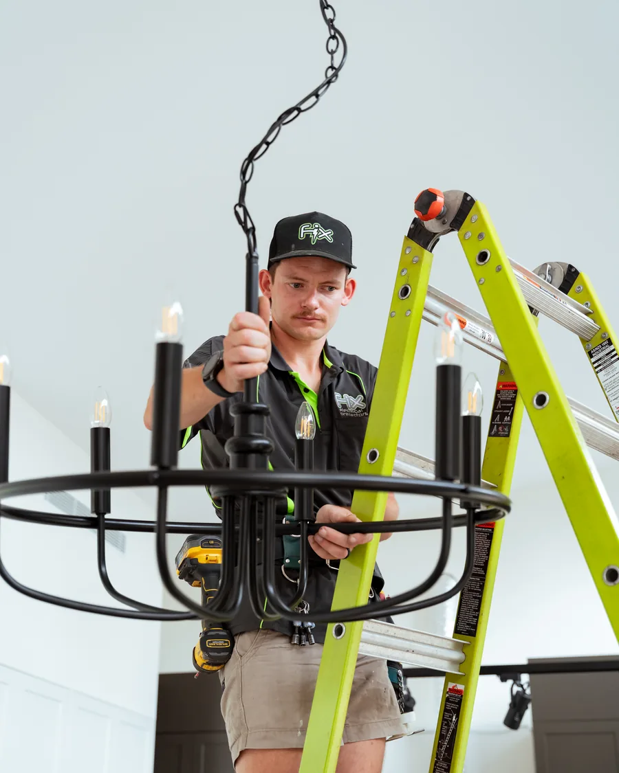 Electrician holding a chandelier fitting before installation