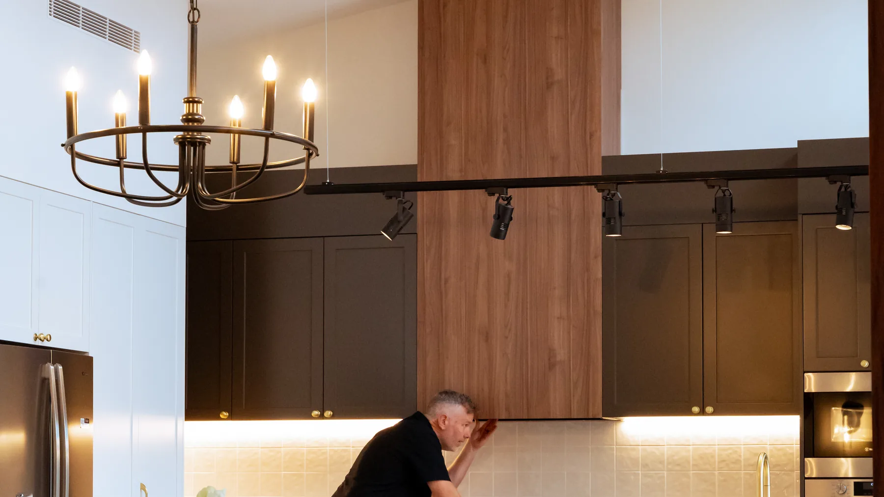 Electrician installing a chandelier above a kitchen island