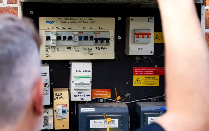Electrician lifting the lid of an outdoor meter box to look at the board