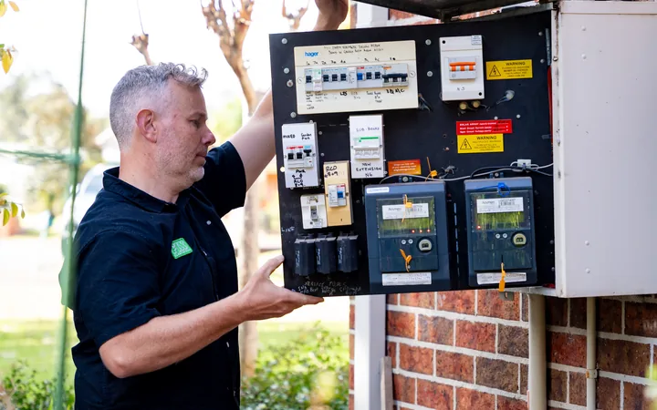 Fix Electrical electrician holding a meter box open while assessing the switchboard