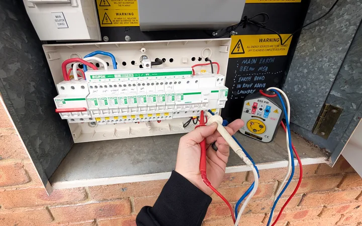 Test probes and a phase rotation tester in use on a finished Clipsal switchboard