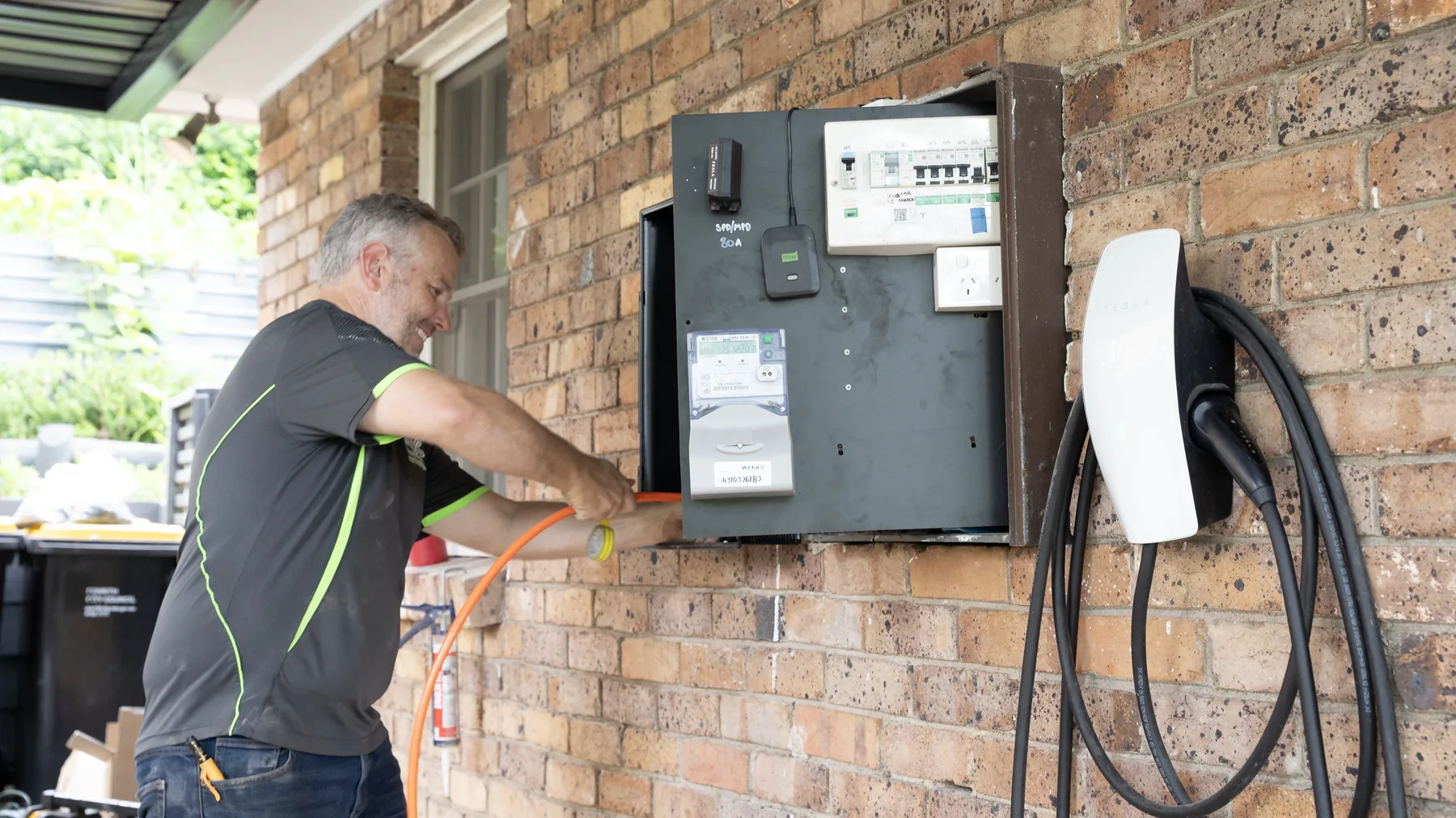 Fix Electrical electrician running conduit into a meter box beside a newly installed EV wall charger