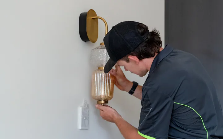 Electrician fitting a wall sconce