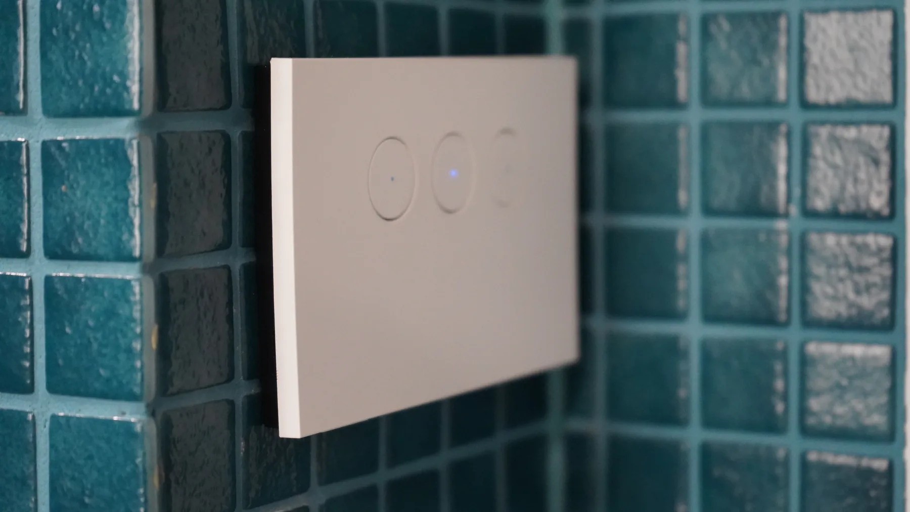 Smart touch light switch with its indicators lit, on a tiled wall